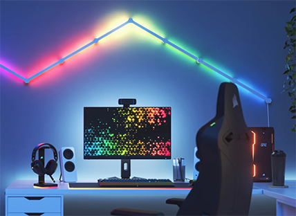 Bild eines PC Setups mit hellblauen RGB Lichtern und ein Regenbogenfarbenen Streifen an der Wand